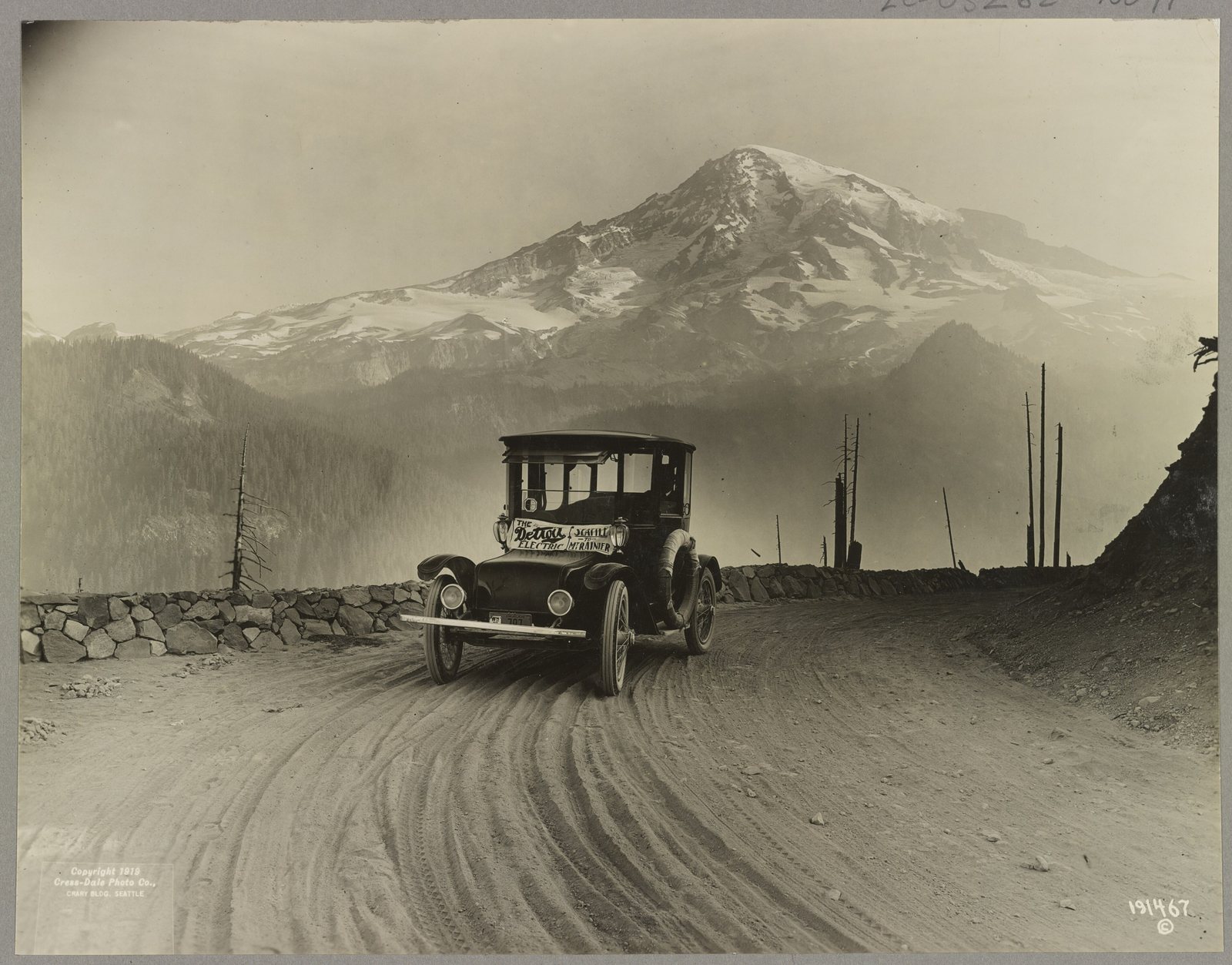 A Detroit Electric car on a mountain road with Mount Rainier behind it, around 1919