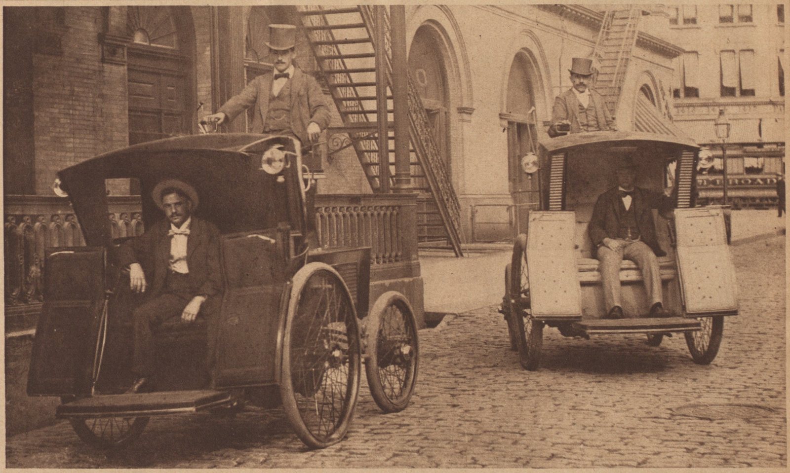 Two early electric cabs with drivers on a New York street in 1898